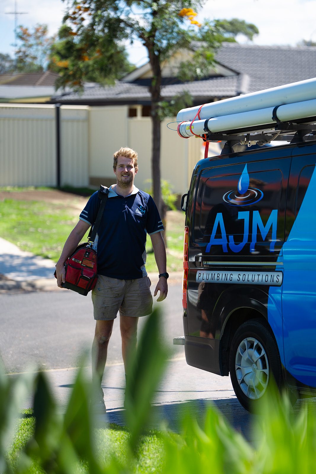 Aaron from AJM Plumbing Solutions walking past the van with his tool bag
